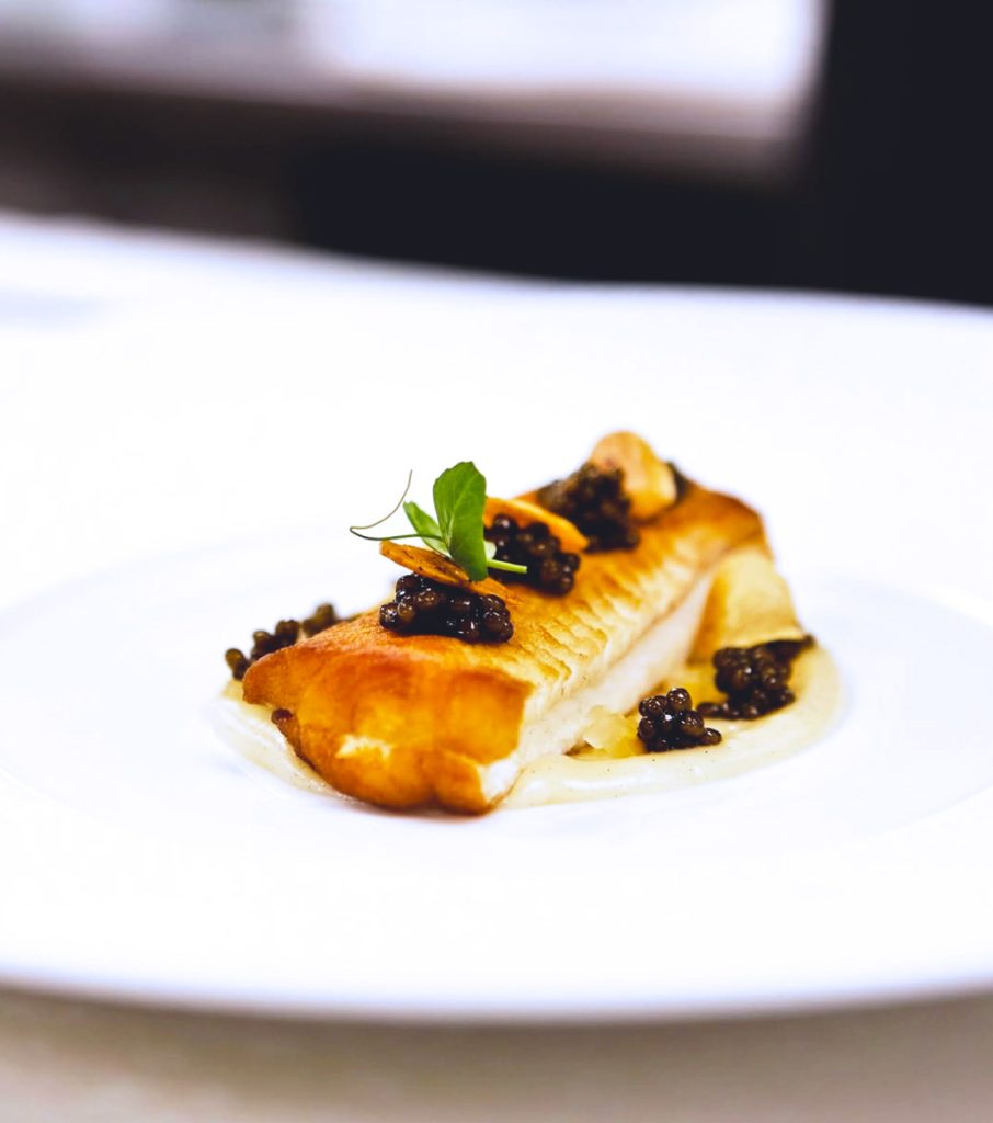 Fine dining at The Ritz-Carlton, Grand Cayman — an elegantly plated Caribbean-inspired dish highlighting the resort’s world-class culinary scene