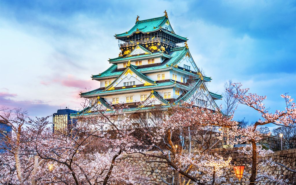 Osaka Castle in Japan with traditional architecture, stone walls, and surrounding gardens